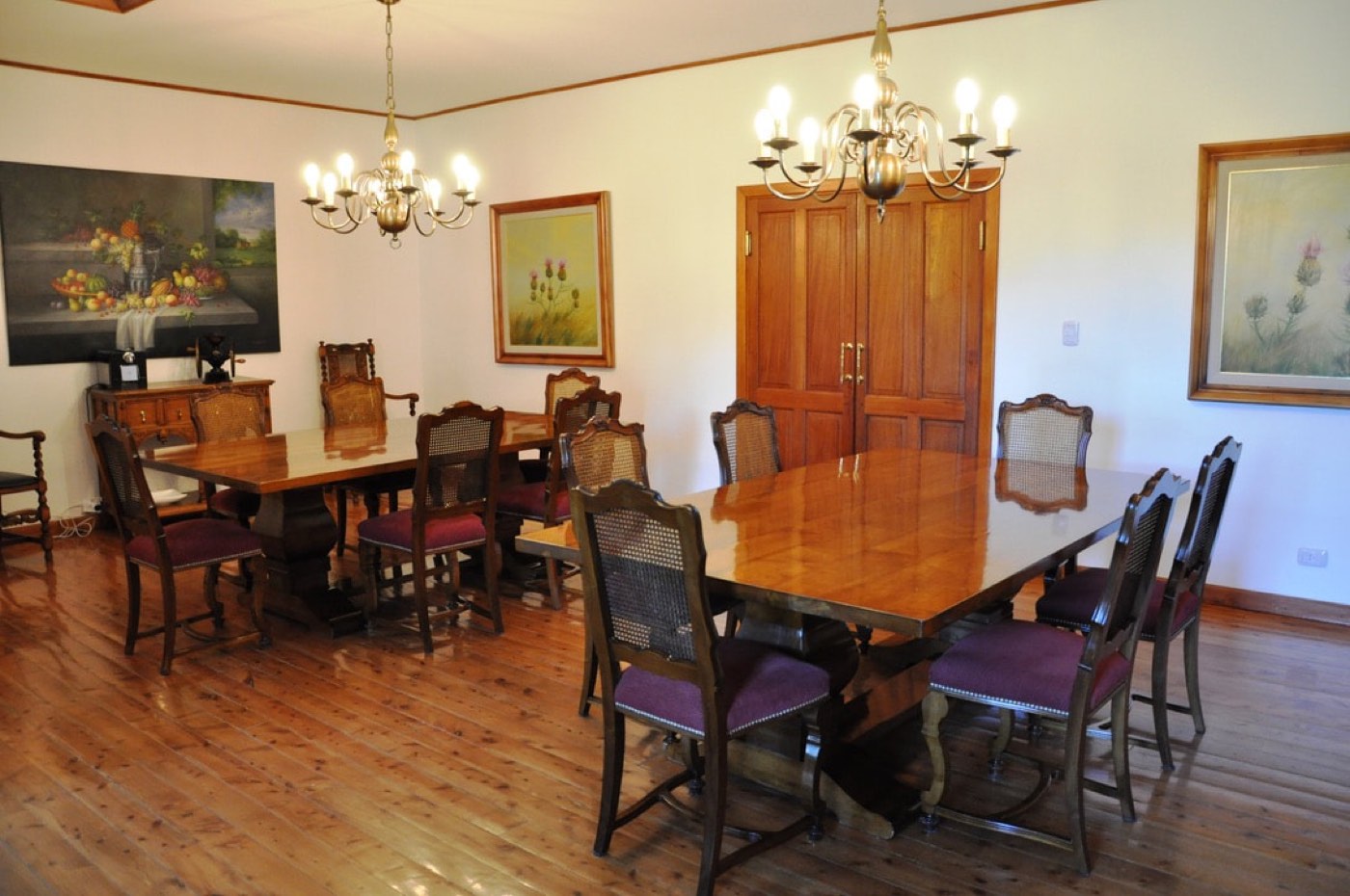The lodge's formal dining room, with two long wooden tables, cane-backed chairs, and brass chandeliers