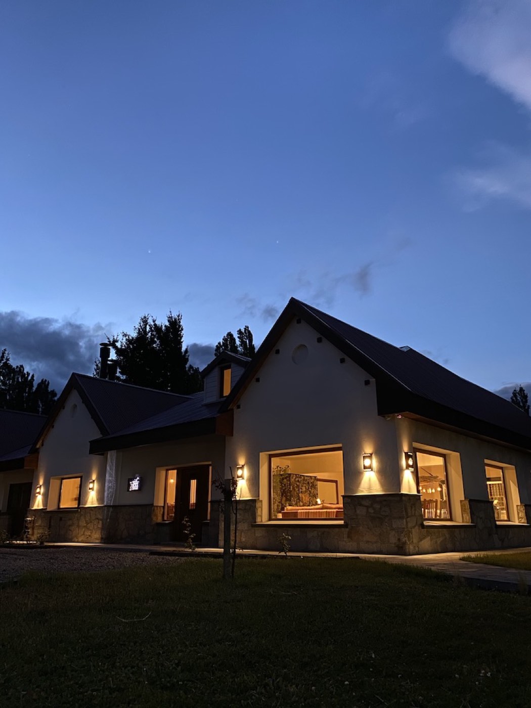 The lodge glowing with warm light at dusk, its windows revealing furnished rooms within