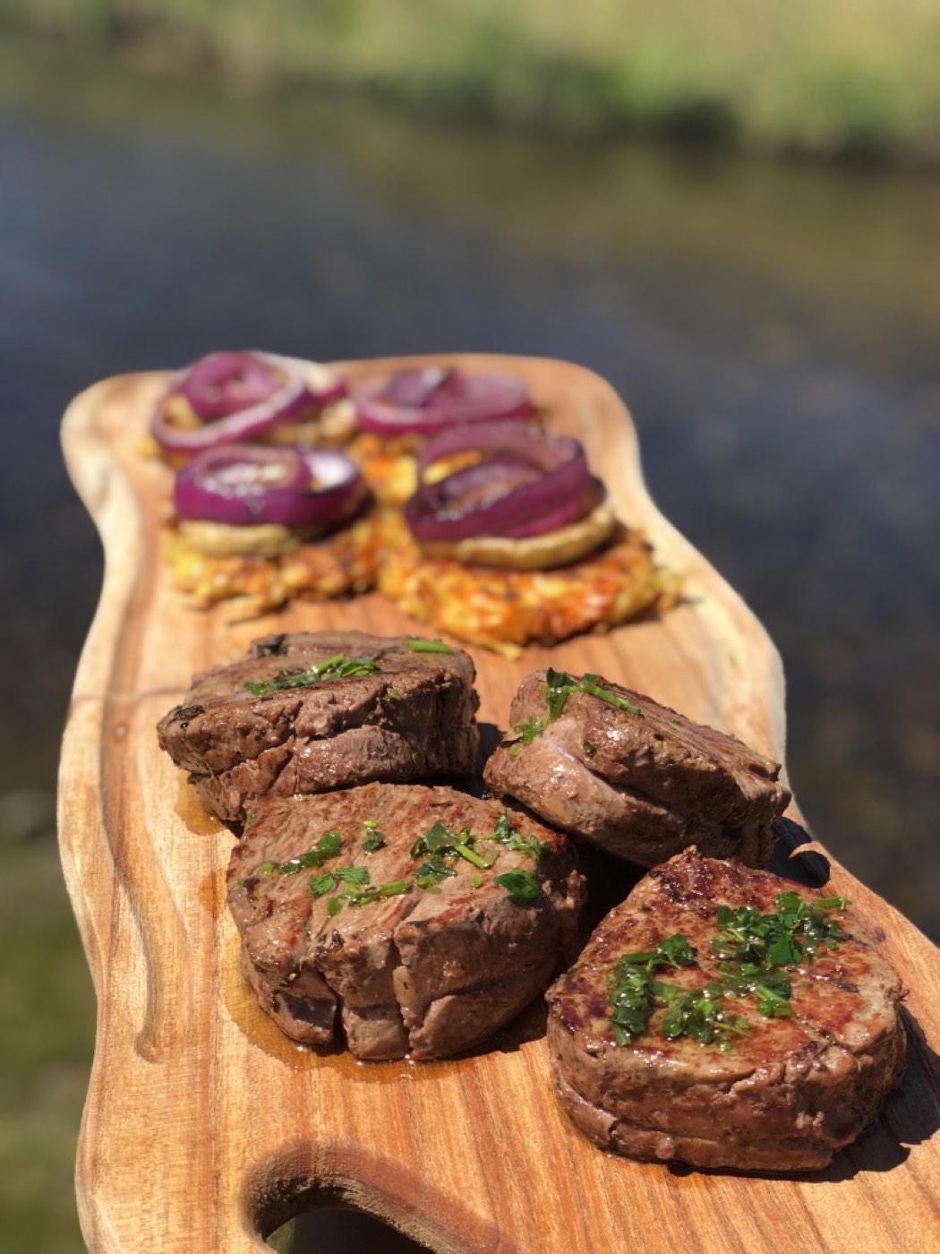 Grilled meat medallions plated with charred red onion and crispy potato rösti