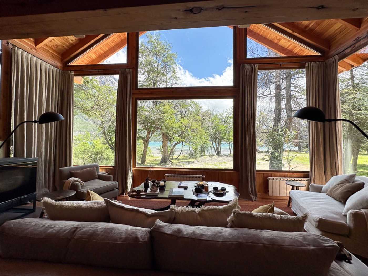 A living room with floor-to-ceiling windows framing the lake and its tree-lined shore