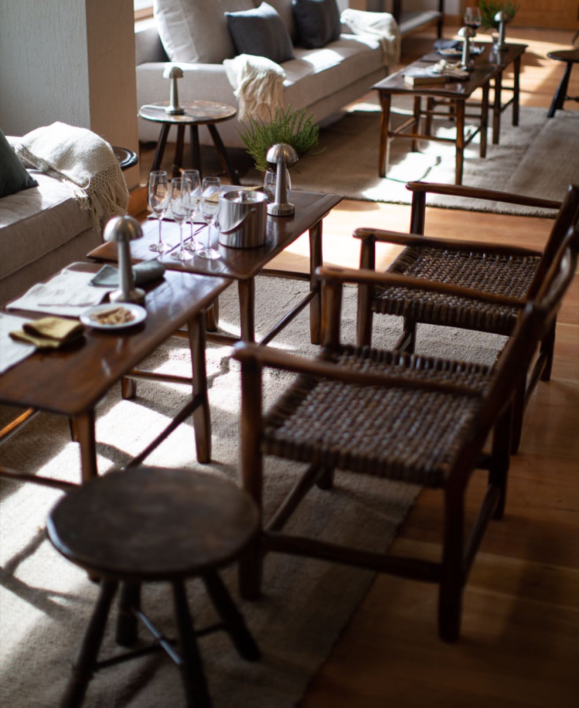 A lounge corner set for evening drinks, with wine glasses, an ice bucket, and woven-seat armchairs