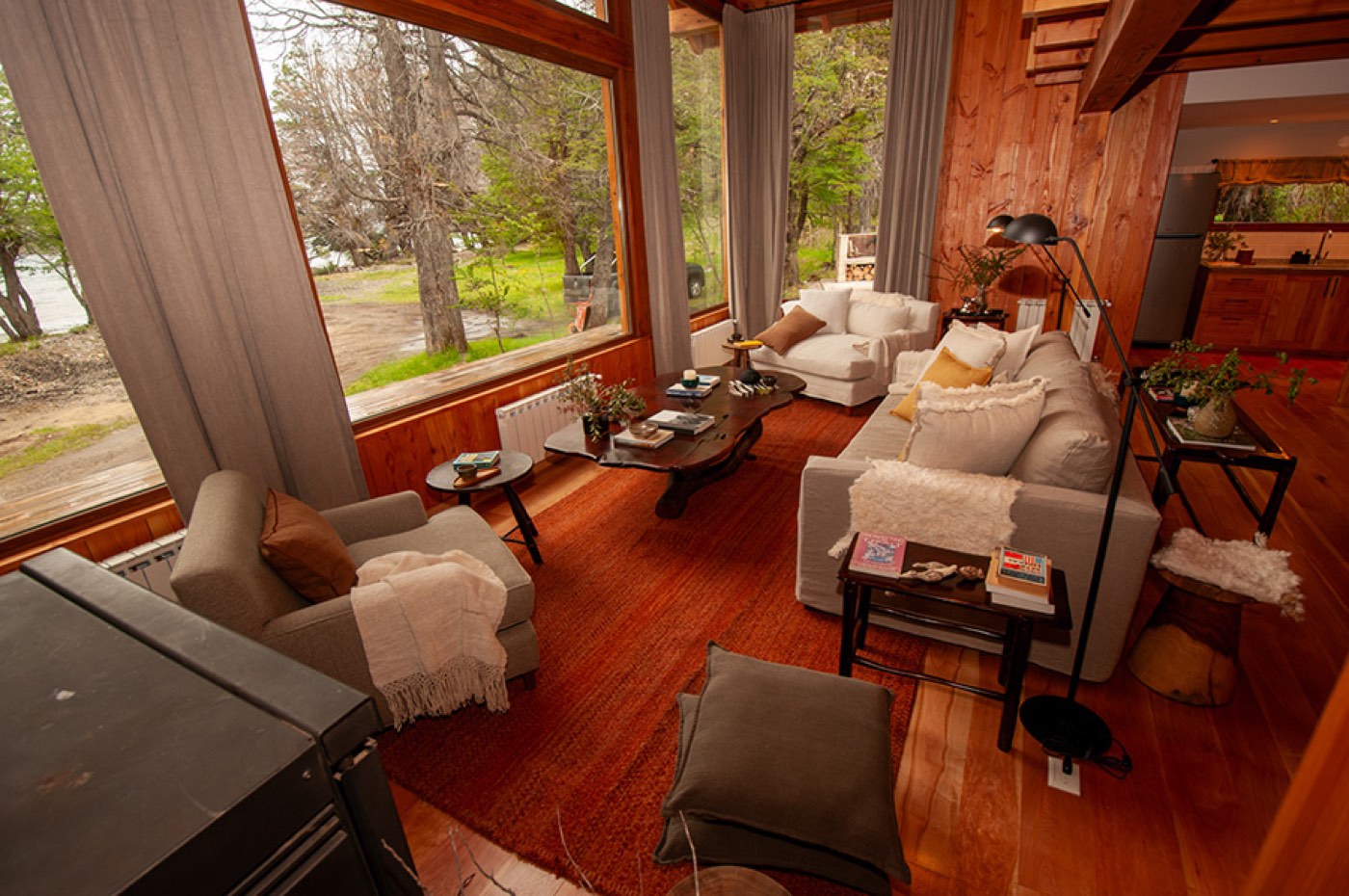 A bright living room in cream tones opening onto the lawn, with the kitchen visible beyond