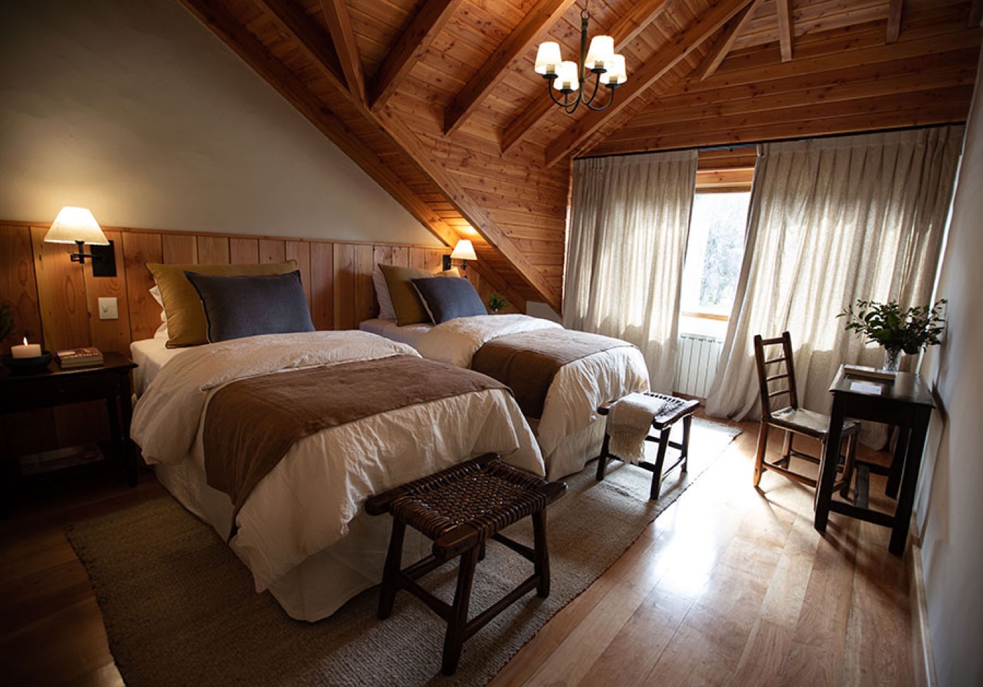 A wood-paneled twin room tucked under a sloped ceiling, with navy and olive accent pillows