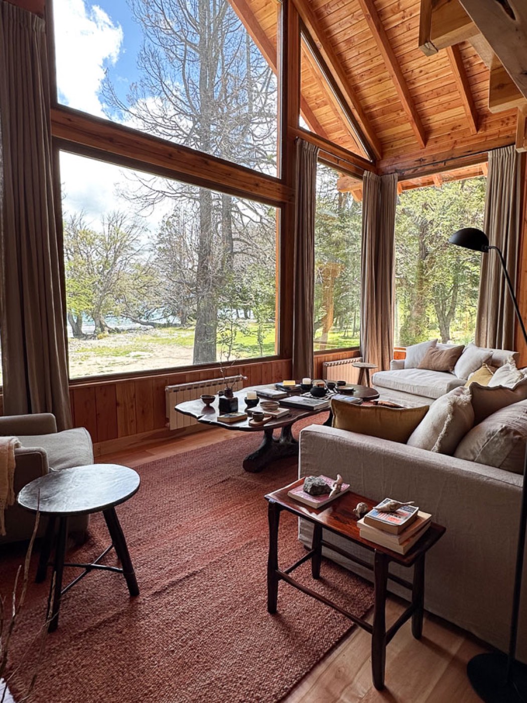 A living room with a live-edge coffee table and picture windows looking out over the lake and forest