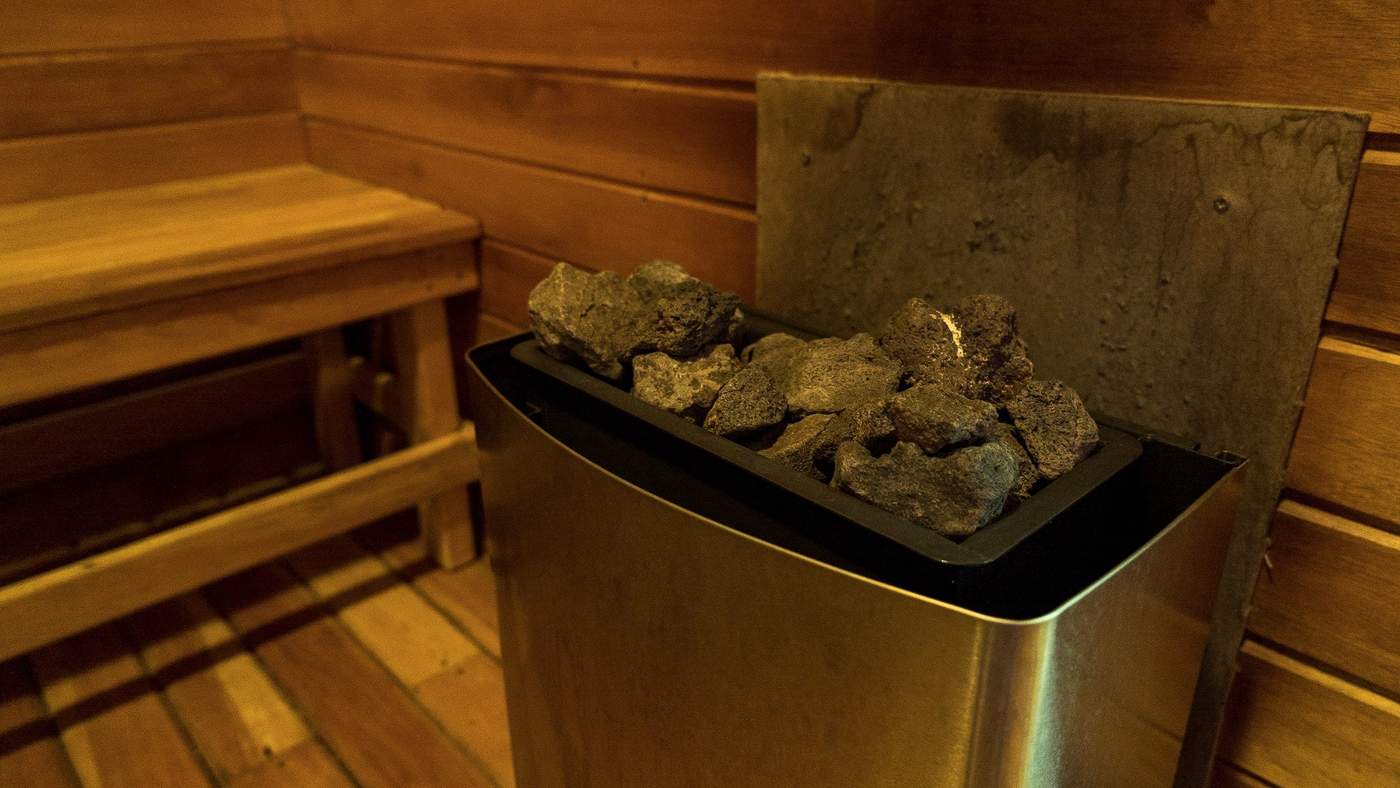 A close view of a sauna's heater, stacked with volcanic rocks glowing under low light