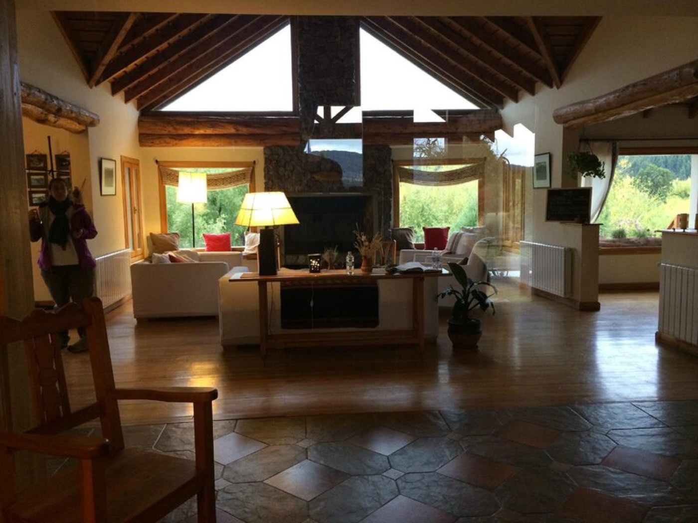 A great room with a vaulted wood-beam ceiling, white sofas with warm-toned pillows, and a stone fireplace