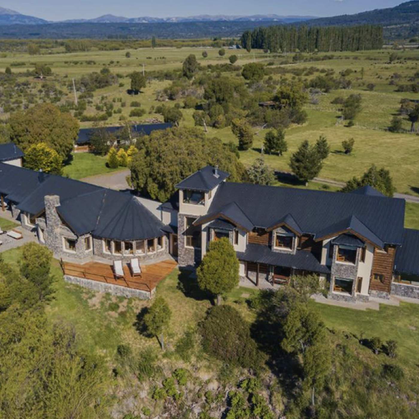 An aerial view of the sprawling lodge complex, its round tower and connected wings set amid open pasture and forest