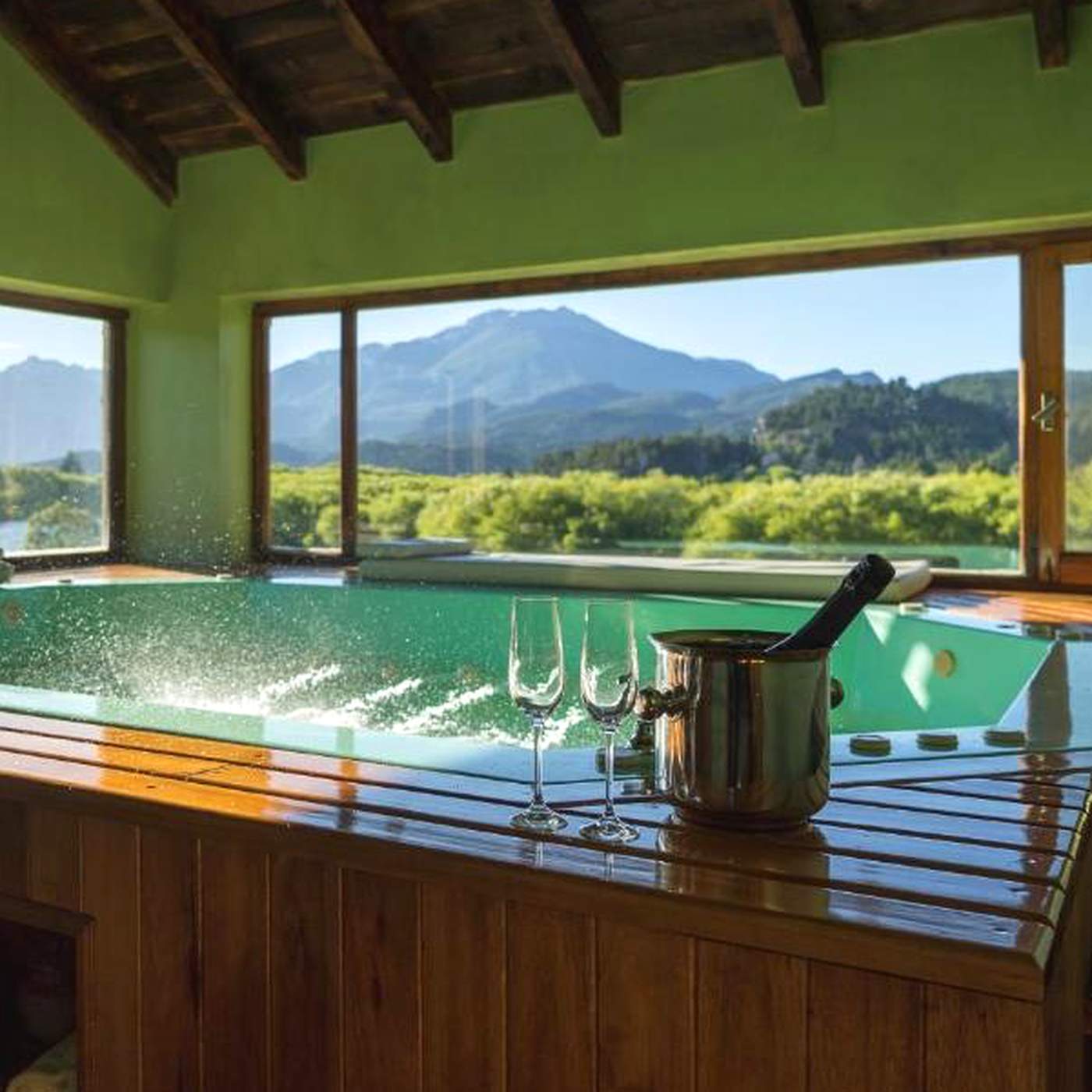 A jetted hot tub with a view of the mountains, champagne flutes and a chilling bottle set on the ledge