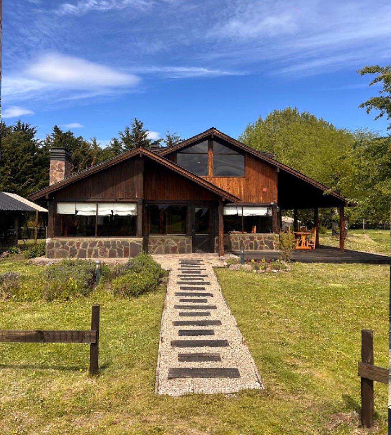 A timber-and-stone lodge exterior with a stepping-stone path through the lawn, one of Patagonia FFL's five partner lodges