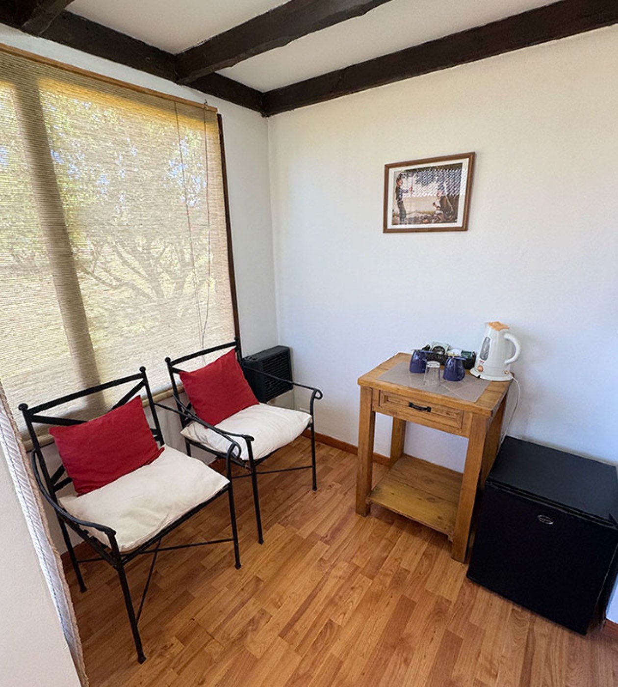 A cozy sitting nook with wrought-iron chairs, a small tea and coffee station, and a mini-fridge
