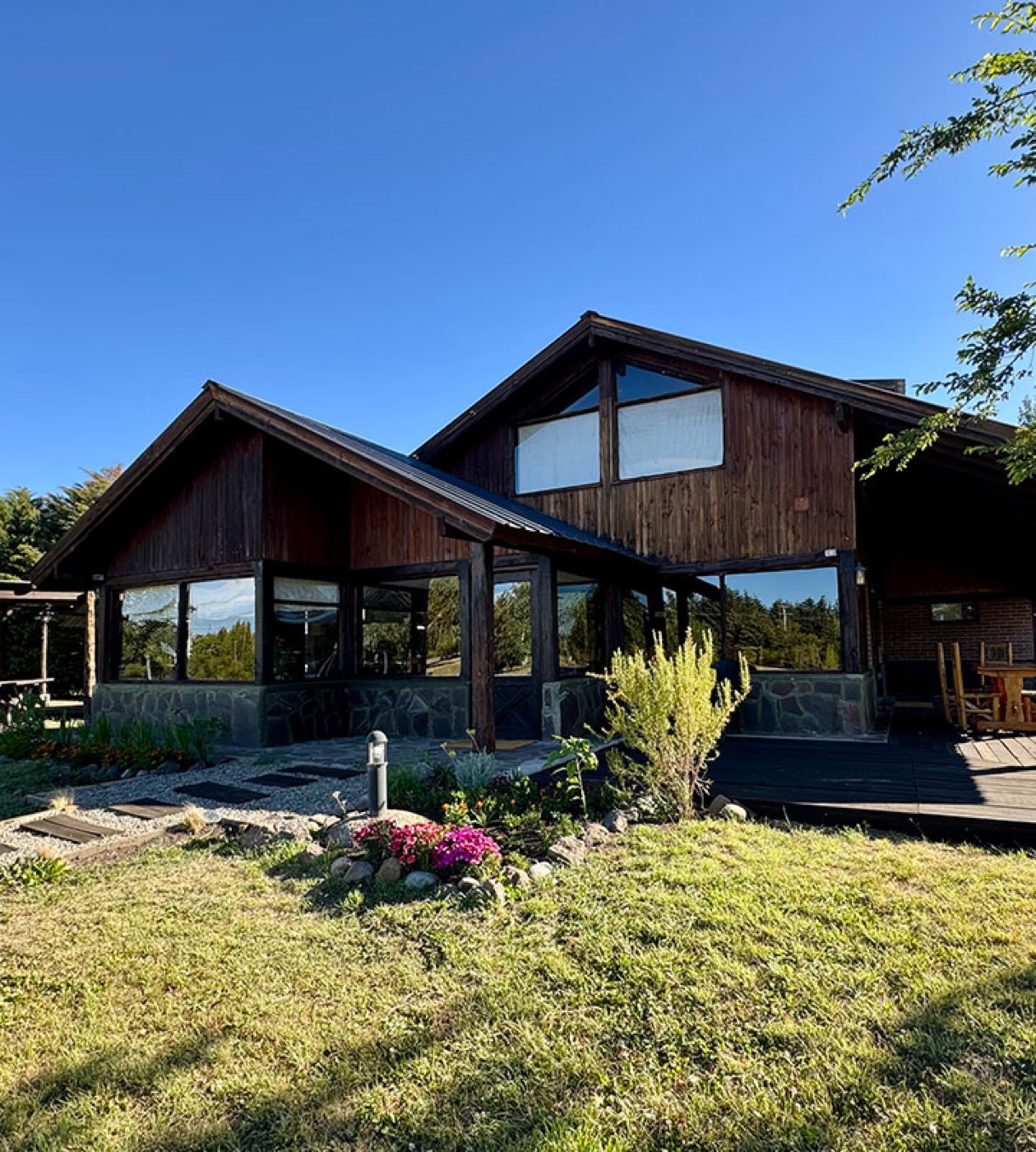 A two-story timber lodge building framed by flowering shrubs